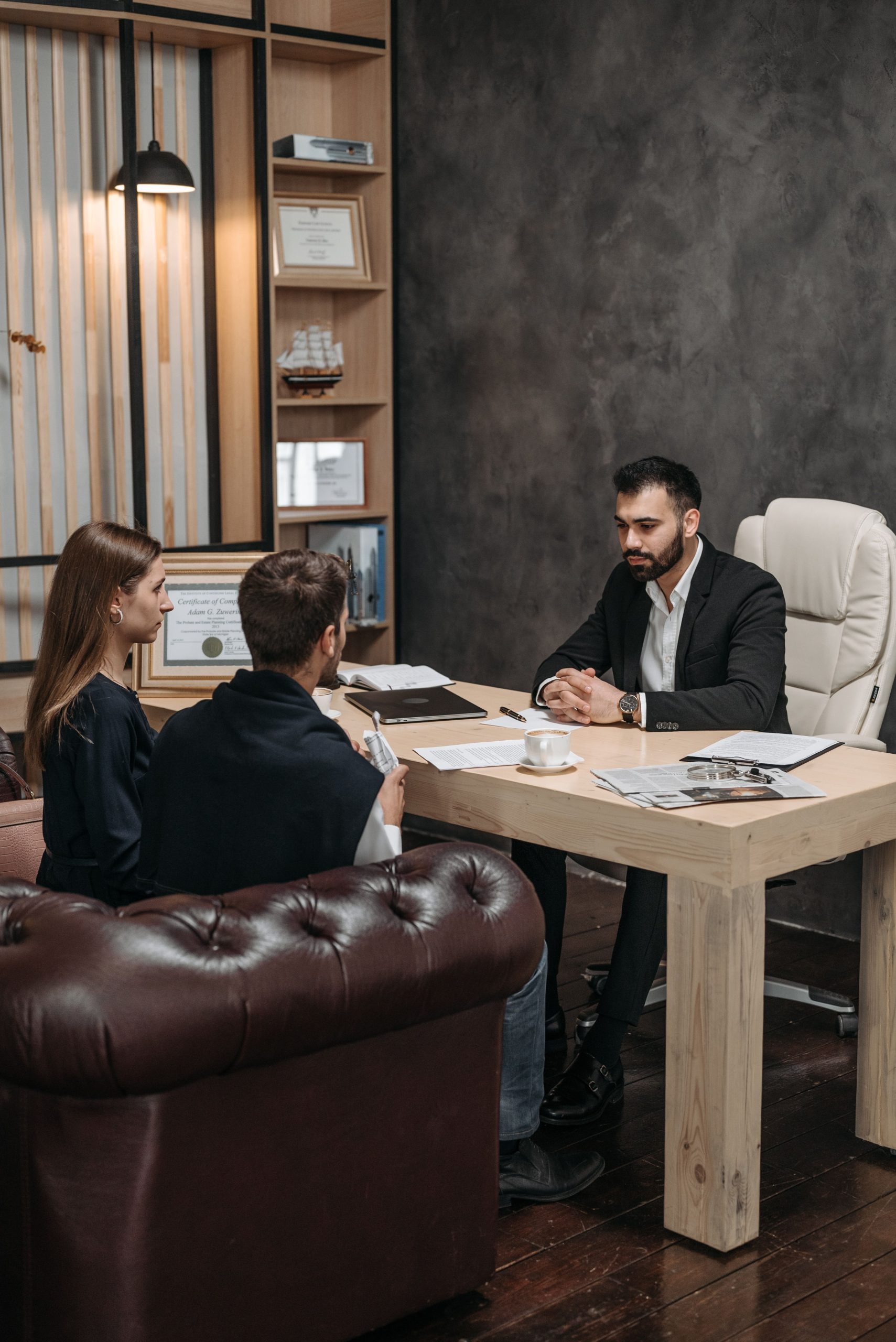 A professional business meeting with three people discussing documents in an office setting.